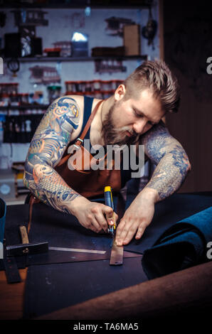 Currier of leather working on a new leather product in the tanner shop Stock Photo