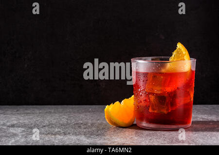 Negroni cocktail with piece of orange in glass on black background. Copyspace Stock Photo
