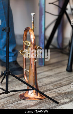 Vintage trumpet stands on grungy wooden floor. It is a brass instrument commonly used in classical and jazz ensembles Stock Photo