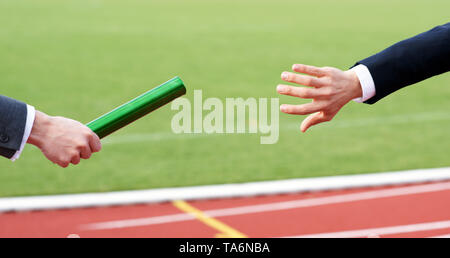 Businessman passing baton in relay race - Concept Teamwork Succession Stock Photo