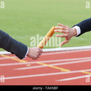 Businessman passing baton in relay race - Concept Teamwork Succession Stock Photo