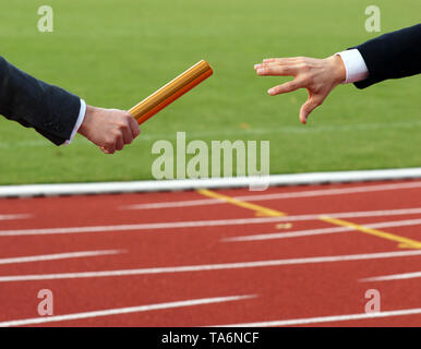 Businessman passing baton in relay race - Concept Teamwork Succession Stock Photo