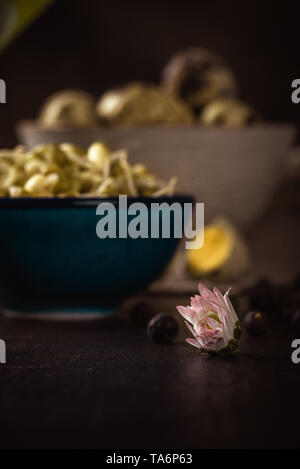 Vertical photo of single daisy bloom with white and red color. Bloom is placed on dark wooden board with mung bean sprouts and quail eggs. Stock Photo