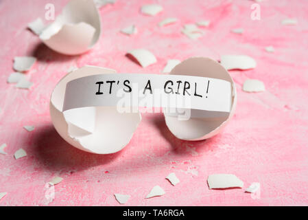 Baby shower concept. Girl, pink. Cracked egg with a message IT'S A GIRL. Like fortune cookies Stock Photo