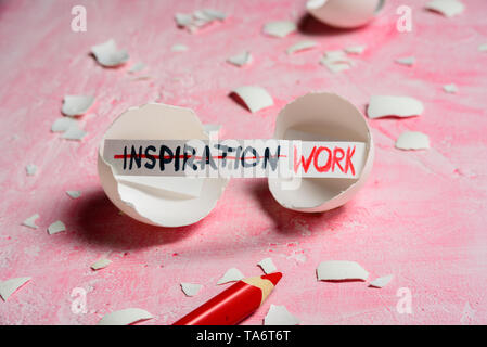 Work hard and inspiration concept. Cracked egg on pink background with text INSPIRATION and WORK. Like fortune cookies Stock Photo
