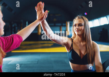 Young attractive girls giving five at sports gym background Stock Photo