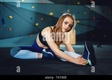 Stretching gymnast girl doing warming exercizes. View of attractive young woman doing sports at crossfit gym Stock Photo