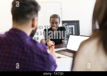 African american hr team welcoming female applicant at job interview, diverse businesswomen shaking hands at multi ethnic group meeting, handshaking a Stock Photo