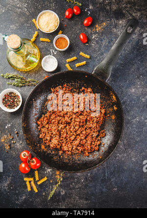 Roasted minced beef in pan and ingredients for classic Italian bolognese sauce on a dark background. Top view or flat-lay. Stock Photo