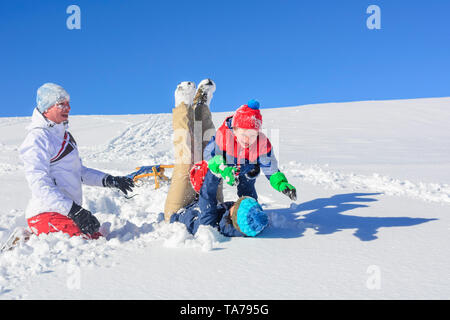 Family has fun in fresh snow at a sunny winter day in austrian alps Stock Photo