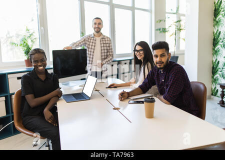 Executive mentor explaining intern or new employee task pointing at computer screen. Man boss supervisor teaching mixed race team to use corporate sof Stock Photo