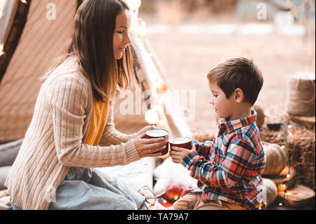 Mother drinking tea with kid son outdoors. Motherhood. Maternity. Stock Photo