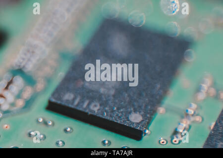 Macro shot of DRAM chip on a green pcb of DDR3 RAM module reveals small trace and components with bokeh. High tech concept. Stock Photo