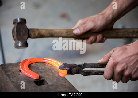 Farrier bending a red-hot horseshoe in the desired shape. Austria Stock Photo