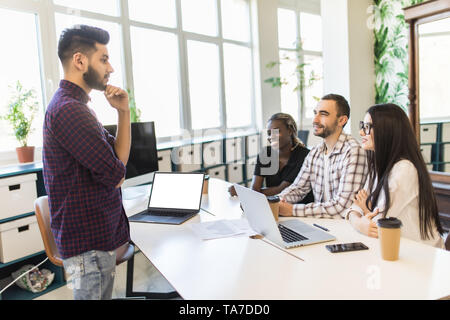 Relaxed informal IT business startup company meeting. Team leader discussing and brainstorming new approaches and ideas with colleagues. Stock Photo