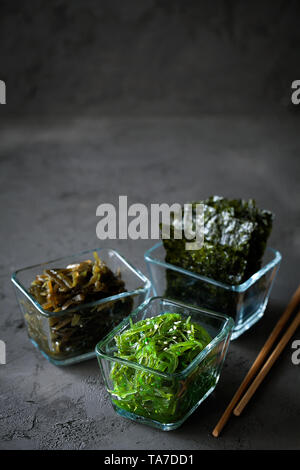 Traditional Japanese Chuka Wakame seaweed salad and crispy roasted nori sheets in glass bowl on dark background top view with copy space Stock Photo