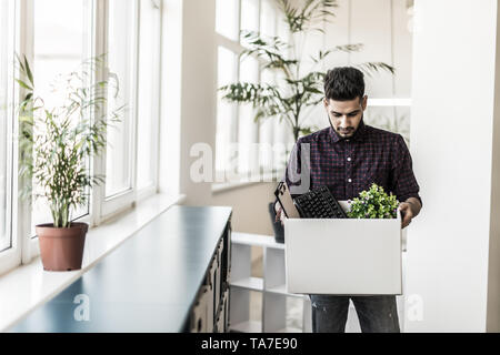 Sad fired indian male office worker holding box of his personal stuff Stock Photo