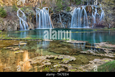 Warm morning sun reflects off the cliffs above the Hanging Lake waterfalls in Dead Horse Canyon near Glenwood Springs, Colorado. Stock Photo