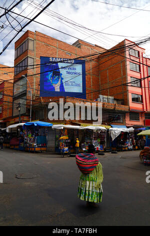 Aymara woman walking past a Samsung technical service electronic billboard in contraband electronics market area, La Paz, Bolivia Stock Photo