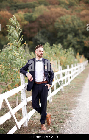 handsome groom wearing suit posing outdoors looking forward wedding day ta7mfd