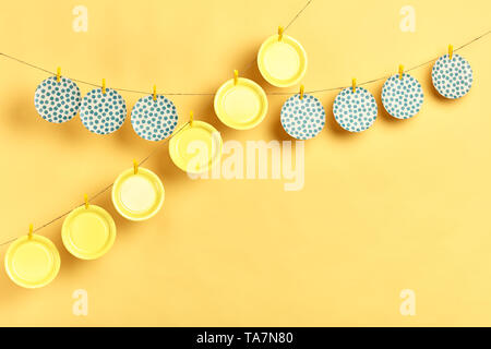 Many clean colorful plates hanging on the rope isolated on yellow background.copy space Stock Photo