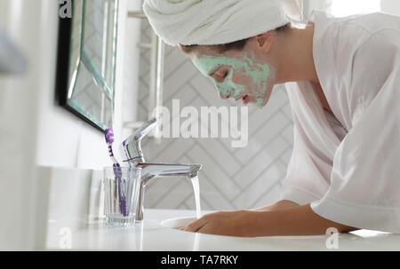 Woman washing her face mask in bathroom sink at home Stock Photo