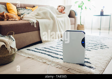 Dehumidifier with touch panel, humidity indicator, uv lamp, air ionizer, water container works at home while woman sleeping. Air dryer Stock Photo