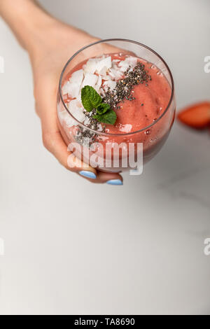 cropped view of woman holding tasty smoothie with coconut flakes on grey Stock Photo