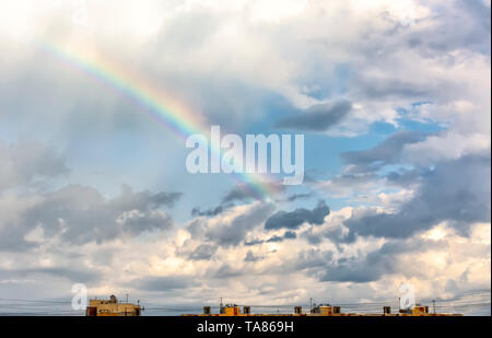 Rainbow in the spring cloudy sky after a thunderstorm and rain. Stock Photo