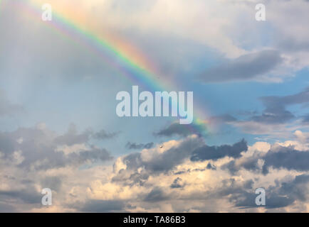 Rainbow in the spring cloudy sky after a thunderstorm and rain. Stock Photo