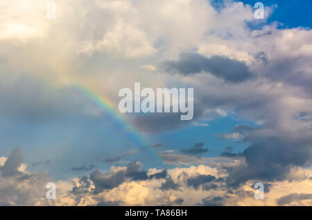 Rainbow in the spring cloudy sky after a thunderstorm and rain. Stock Photo