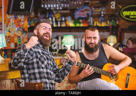 Relaxation in pub. Friends relaxing in pub. Live music concert. Man play guitar in pub. Stock Photo