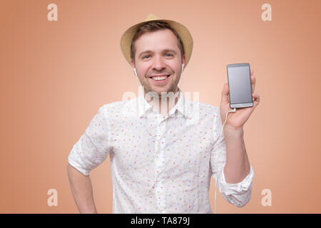 Smiling man in summer hat holding mobile phone Stock Photo