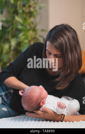 Happy mother giving cuddles and playing smiling with her cute newborn. Family, new life, childhood, beginning concept. Stock Photo