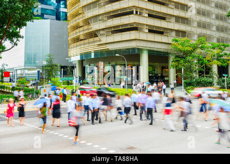 Crowd of business people cross a road by the office buildings in Singapore Downtown. Motion blur Stock Photo