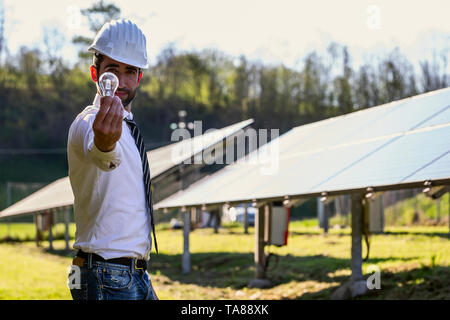Technical expert in solar photovoltaic panels, remote control performs routine actions to monitor the system using clean renewable energy in the hand  Stock Photo