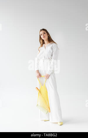 pretty young woman holding yellow string bag with baguette and bottle of milk on white Stock Photo