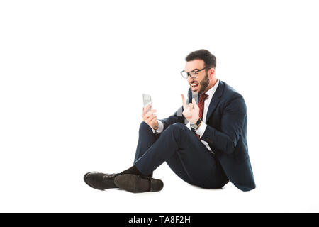 angry businessman having video chat and showing middle finger while sitting on white background Stock Photo