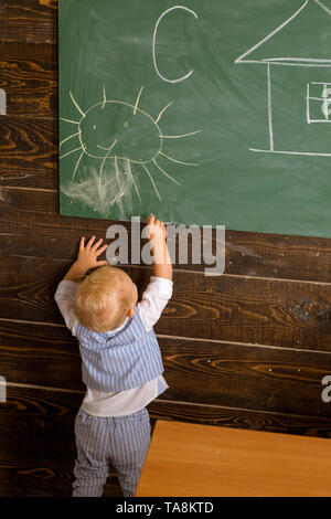 Little boy learn drawing on classroom chalkboard. Child have lesson in drawing in school. Every child is an artist Stock Photo