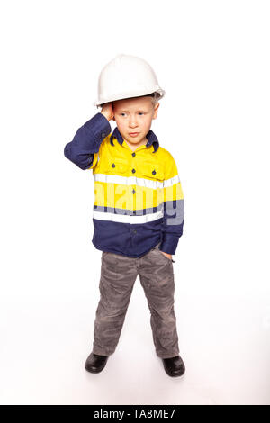 Young blond causacian boy scratching his head in disbelief role playing as a frustrated construction worker in a yellow and blue hi-viz shirt, boots,  Stock Photo