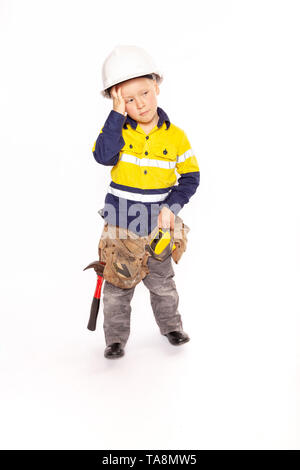 Young blond caucasian boy scratching his head in disbelief role playing as a frustrated construction worker in a yellow and blue hi-viz shirt, boots,  Stock Photo