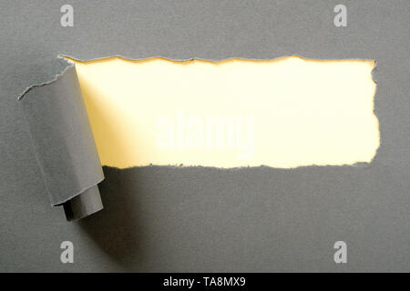 Gray paper torn ripped strip yellow background Stock Photo