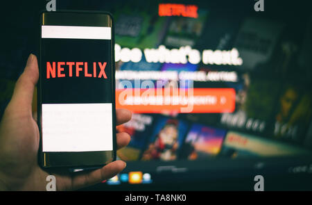 Netflix app on smartphone in hand service watching entertainment and movies with Netflix on Laptop screen background - January 11 2018 Bangkok Thailan Stock Photo