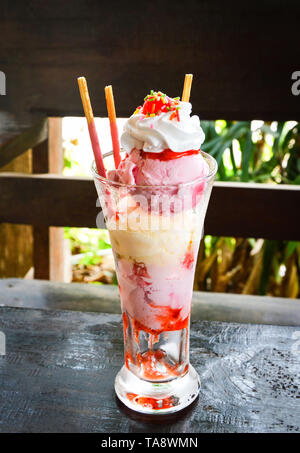 ice cream in a glass / Vanilla and  strawberry ice cream with cracker sticks in glass on table rustic wood background Stock Photo