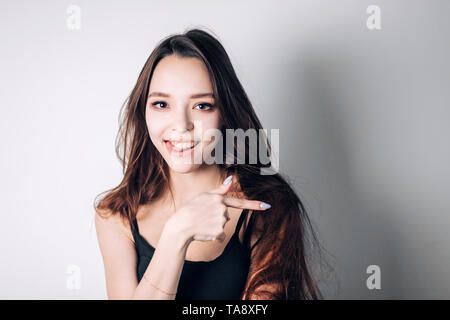 Woman surprise showing product. Beautiful girl with pointing to the side. Presenting your product. Expressive facial expressions emotions Stock Photo