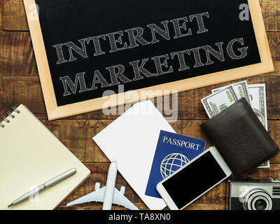 internet marketing handwritten with white chalk on a blackboard, money wallet , notebook and smartphone on a wooden background Stock Photo