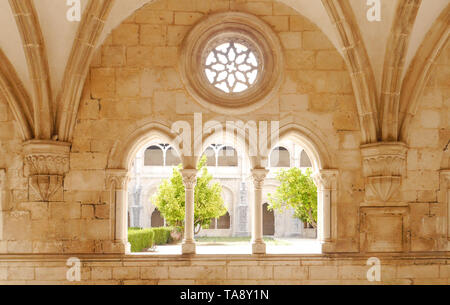 Alcobaca, Portugal - August 2018: View of cloister garden through the arch and rose windows of the Alcobaca Monastery. Stock Photo