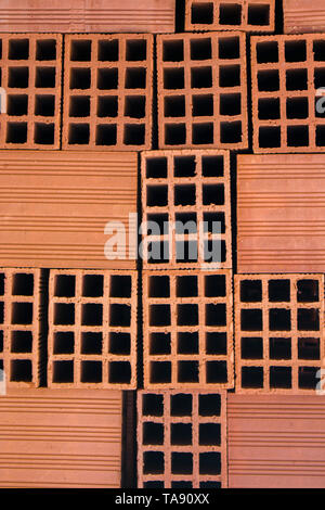 Red hollow blocks haphazardly arranged into a stack. Interesting construction texture or background with copy space. Stock Photo
