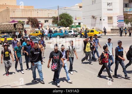 TUNISIA-CIRCA MAY, 2012: Group of aggressive young teenagers walk across the road on the streets of Tunisian provincial town. Schoolboys and students  Stock Photo