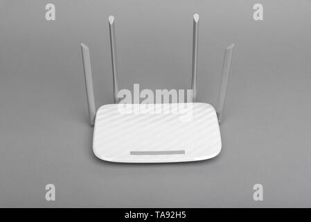 White modern Wi-Fi router with four antennas on gray background. Stock Photo